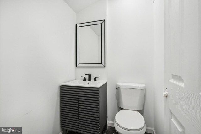 bathroom featuring toilet, vanity, and lofted ceiling