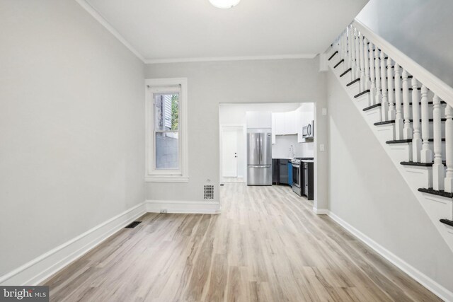 unfurnished living room featuring ornamental molding and light hardwood / wood-style flooring