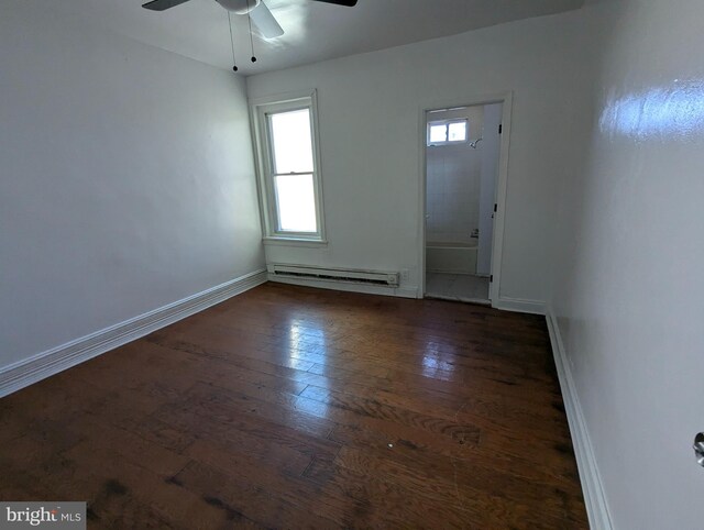 unfurnished room with ceiling fan, dark wood-type flooring, and a baseboard heating unit