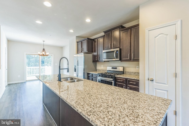 kitchen featuring a center island with sink, dark wood-type flooring, appliances with stainless steel finishes, and light stone countertops