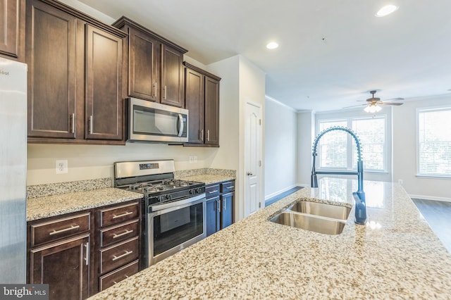 kitchen with hardwood / wood-style floors, sink, appliances with stainless steel finishes, and light stone countertops