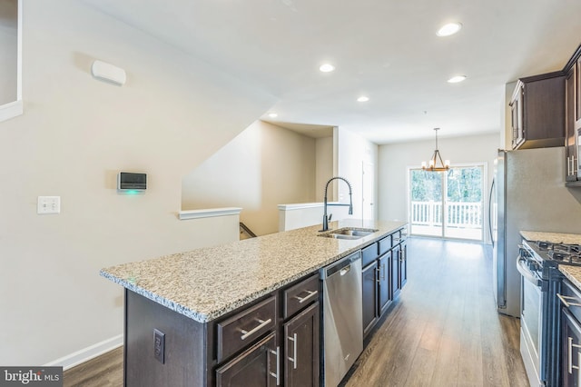 kitchen with sink, gas stove, stainless steel dishwasher, dark wood-type flooring, and a kitchen island with sink