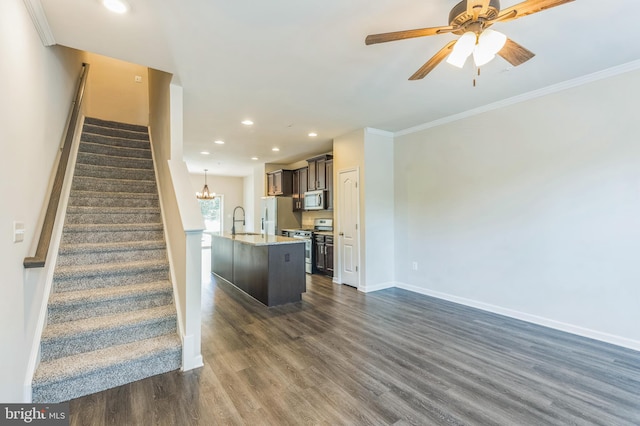 interior space featuring appliances with stainless steel finishes, a kitchen island with sink, dark hardwood / wood-style floors, ornamental molding, and sink