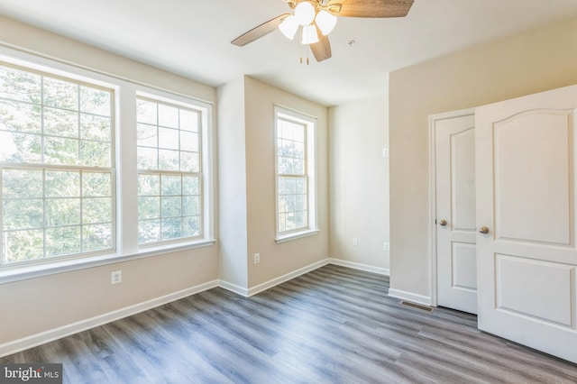 unfurnished bedroom with ceiling fan, multiple windows, and hardwood / wood-style flooring