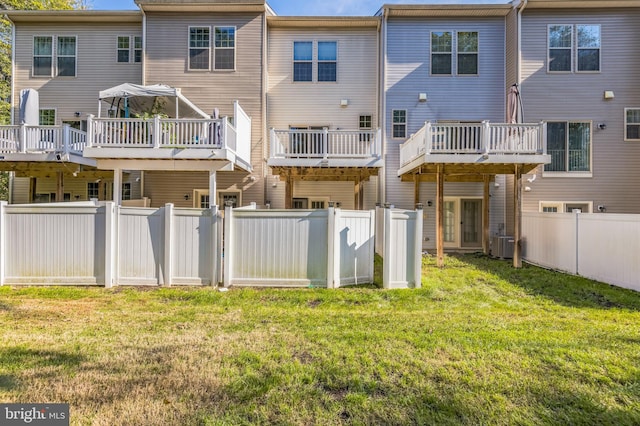 back of house featuring cooling unit, a deck, and a lawn