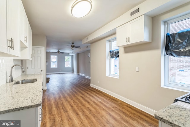 kitchen with white cabinets, light stone countertops, sink, and hardwood / wood-style floors