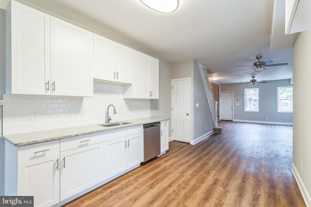 kitchen featuring white cabinets, tasteful backsplash, stainless steel dishwasher, light hardwood / wood-style flooring, and sink