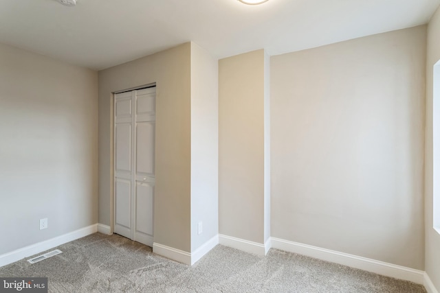 unfurnished bedroom with a closet and light carpet