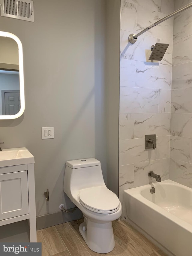 full bathroom with tiled shower / bath, vanity, wood-type flooring, and toilet