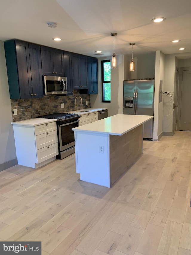 kitchen with sink, appliances with stainless steel finishes, light hardwood / wood-style flooring, and decorative light fixtures