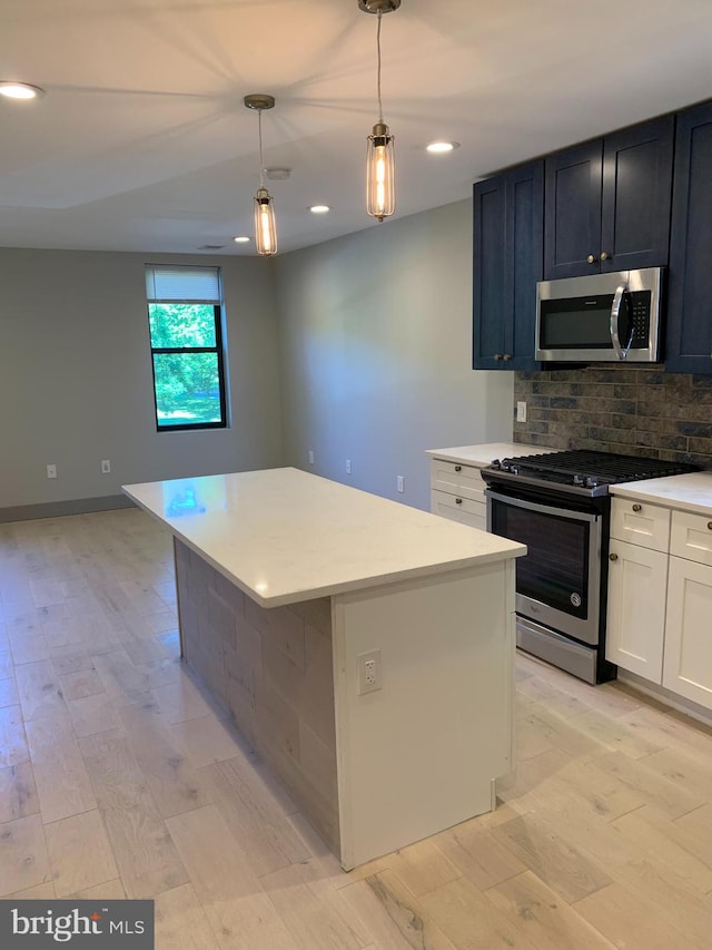 kitchen with appliances with stainless steel finishes, light hardwood / wood-style flooring, decorative light fixtures, and a kitchen island