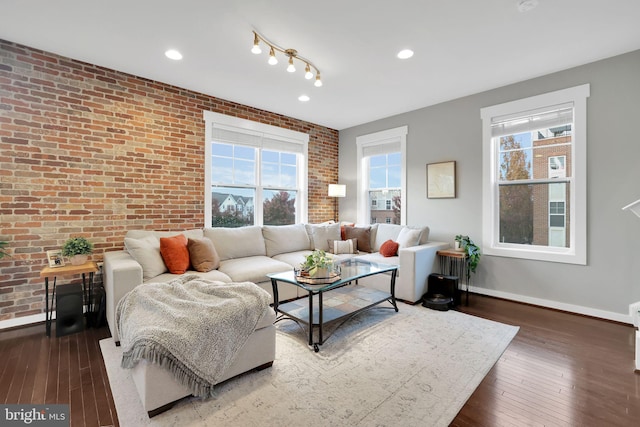 living room with dark hardwood / wood-style flooring and brick wall