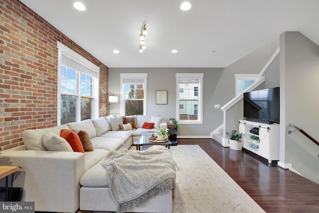 living room with plenty of natural light, brick wall, and dark hardwood / wood-style floors