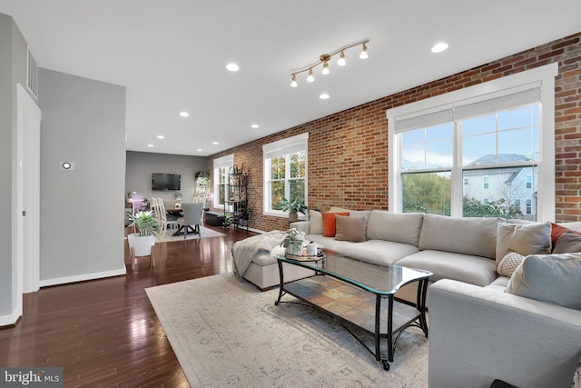 living room with dark hardwood / wood-style flooring and brick wall