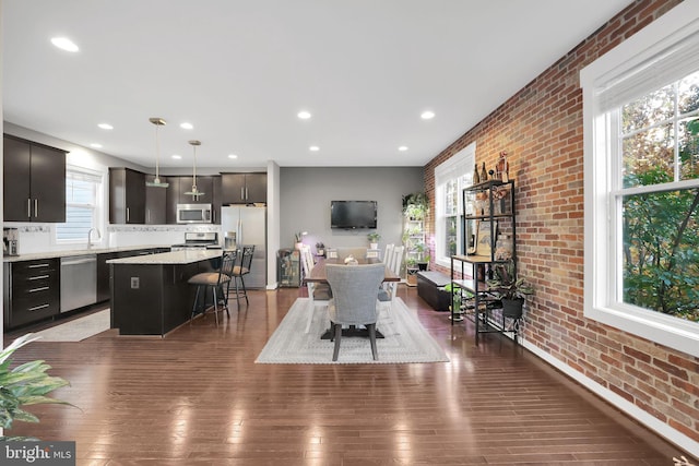 dining space with dark hardwood / wood-style flooring, sink, and brick wall