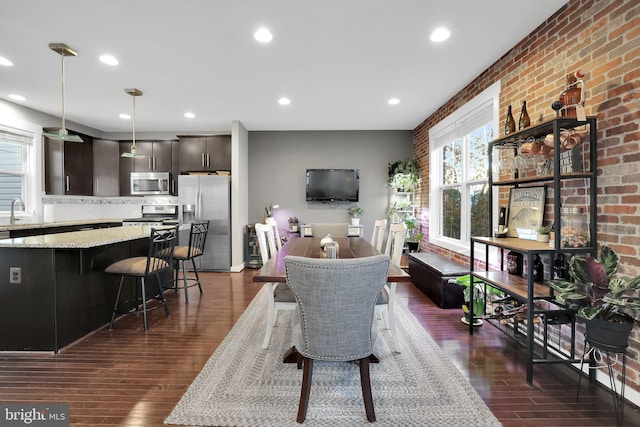 dining room with dark wood-type flooring, sink, and brick wall