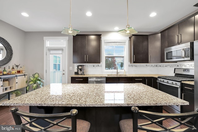 kitchen featuring appliances with stainless steel finishes, dark brown cabinets, a kitchen breakfast bar, and a center island