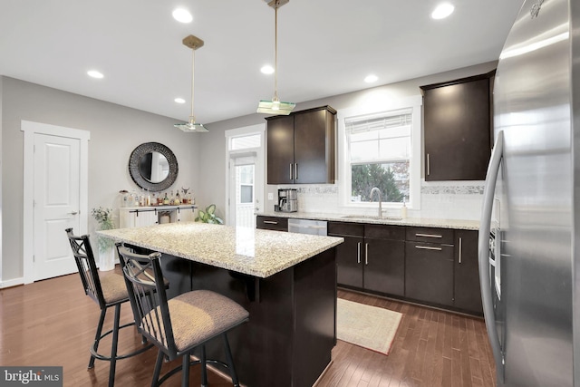 kitchen featuring stainless steel appliances, dark wood-type flooring, a kitchen island, backsplash, and dark brown cabinets