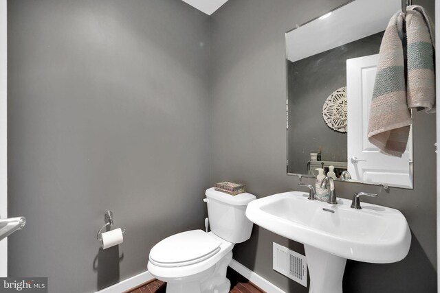 bathroom featuring toilet, sink, and hardwood / wood-style flooring