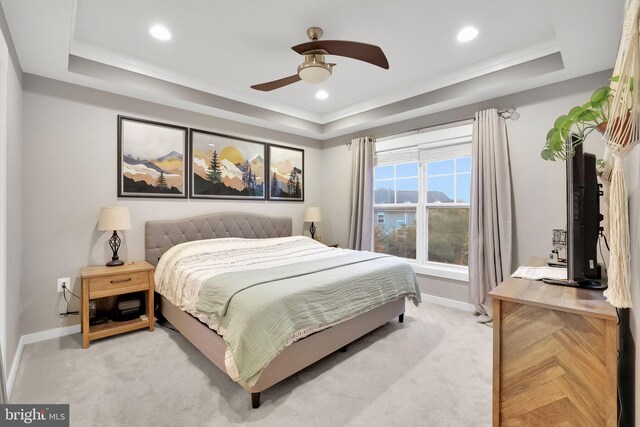 carpeted bedroom with ceiling fan and a tray ceiling