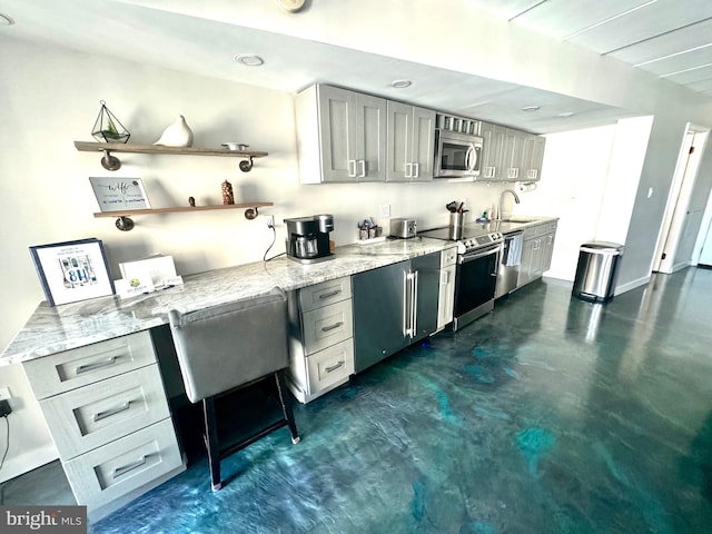 kitchen with light stone countertops, sink, appliances with stainless steel finishes, and gray cabinetry