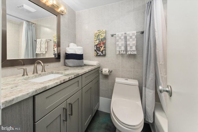 bathroom with vanity, toilet, and tile walls