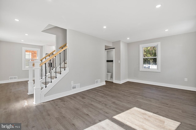 unfurnished living room featuring wood finished floors, recessed lighting, baseboards, and stairway