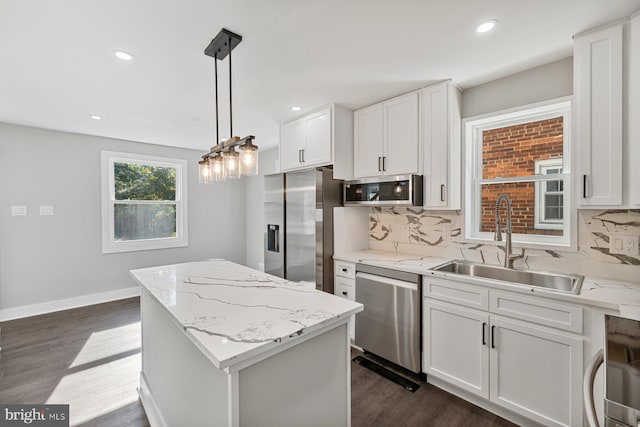 kitchen with appliances with stainless steel finishes, a sink, a center island, backsplash, and recessed lighting