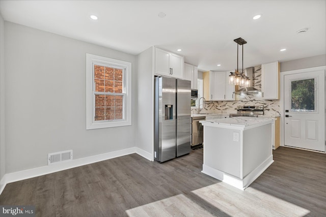 kitchen featuring stainless steel appliances, wall chimney exhaust hood, dark wood finished floors, white cabinetry, and backsplash