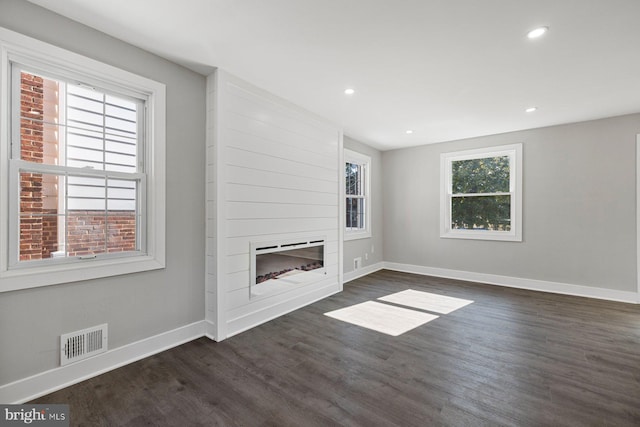 unfurnished living room with dark wood-style floors, baseboards, a fireplace, and recessed lighting