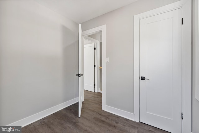 unfurnished bedroom featuring baseboards and dark wood-type flooring