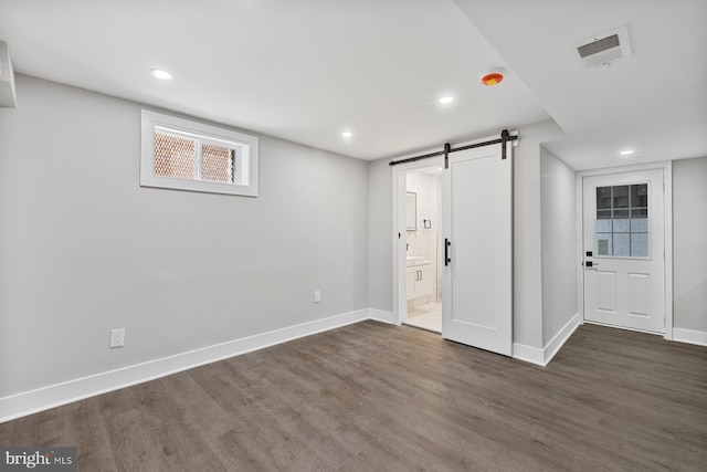 below grade area featuring a barn door, wood finished floors, baseboards, and recessed lighting
