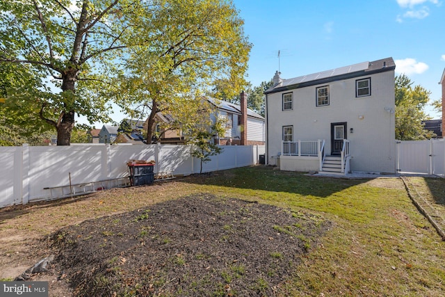 back of house featuring a gate and roof mounted solar panels