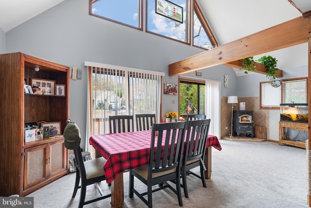 carpeted dining room featuring a wood stove and high vaulted ceiling