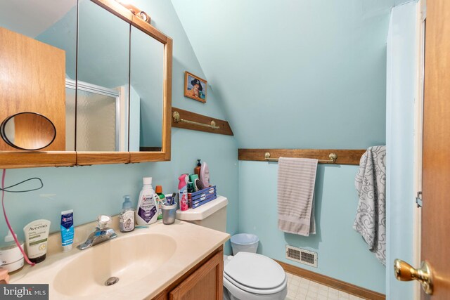 bathroom with vanity, toilet, and lofted ceiling