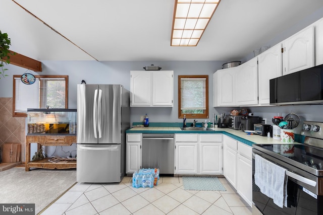 kitchen featuring white cabinets, decorative backsplash, light tile patterned flooring, and appliances with stainless steel finishes