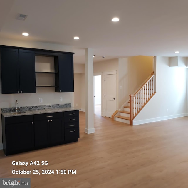 kitchen with light stone countertops, sink, and light wood-type flooring