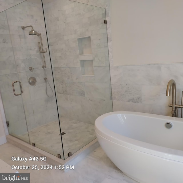 bathroom featuring tile walls and separate shower and tub