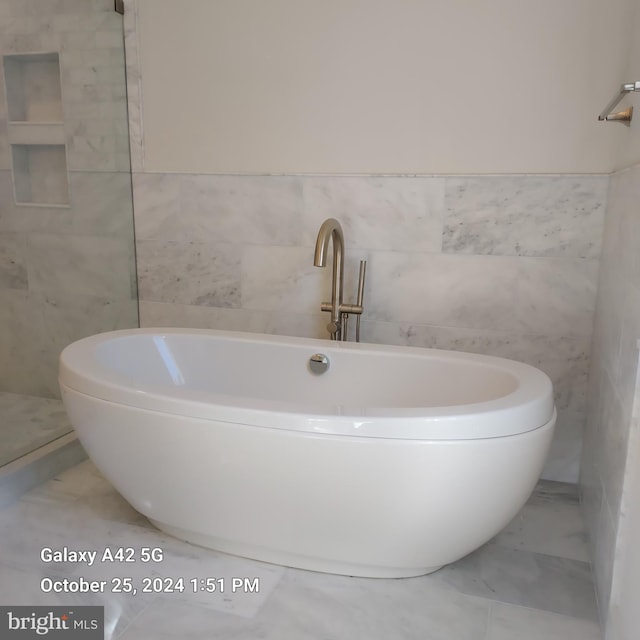 bathroom featuring a bath and tile walls