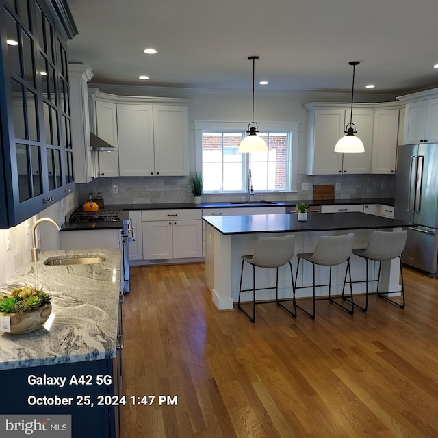 kitchen with white cabinets, wood-type flooring, sink, a center island, and premium appliances