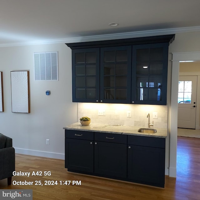 bar featuring crown molding, tasteful backsplash, and hardwood / wood-style floors