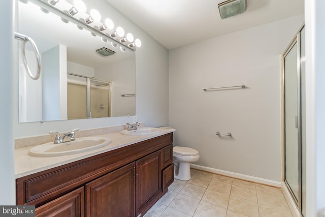 bathroom with vanity, toilet, a shower with shower door, and tile patterned floors