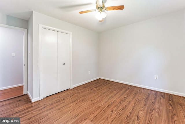 unfurnished bedroom featuring hardwood / wood-style floors, a closet, and ceiling fan