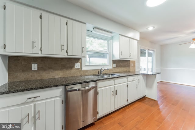 kitchen featuring sink, dishwasher, white cabinetry, dark stone countertops, and light hardwood / wood-style flooring