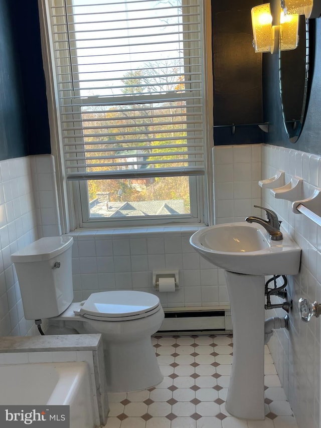 bathroom featuring sink, toilet, baseboard heating, and tile walls