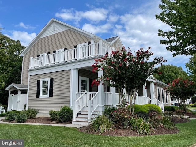 view of front facade with a balcony, a front yard, and covered porch