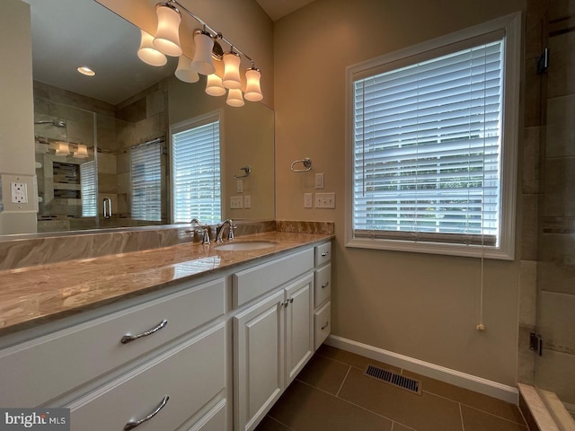 bathroom with vanity, a healthy amount of sunlight, walk in shower, and tile patterned flooring