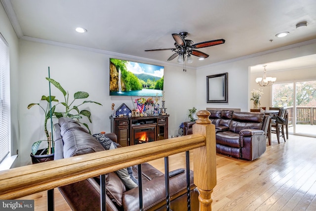 living room with ceiling fan with notable chandelier, light hardwood / wood-style flooring, and ornamental molding