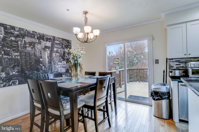 dining room with a chandelier, light wood-type flooring, and ornamental molding