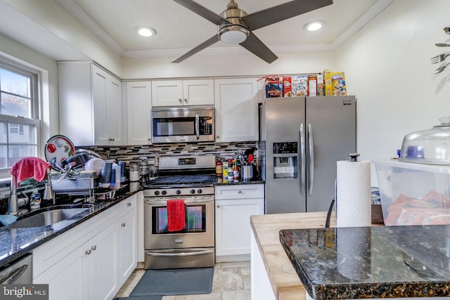 kitchen with white cabinetry, appliances with stainless steel finishes, backsplash, dark stone countertops, and ceiling fan